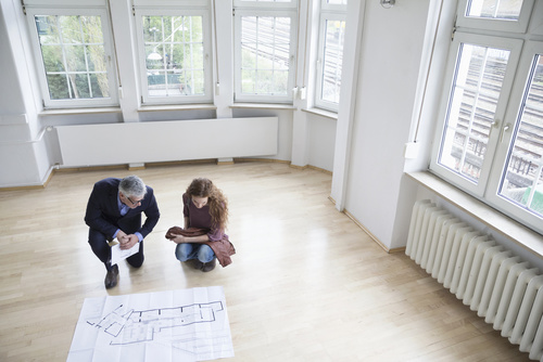 Real estate agent showing construction plan to client in empty a Real estate agent showing construction plan to client in empty a
